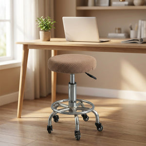 Housse de chaise ronde beige sur tabouret sous un bureau en bois clair