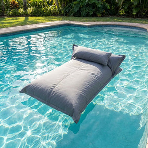 Pouf flottant gris flottant sur l'eau turquoise d'une piscine