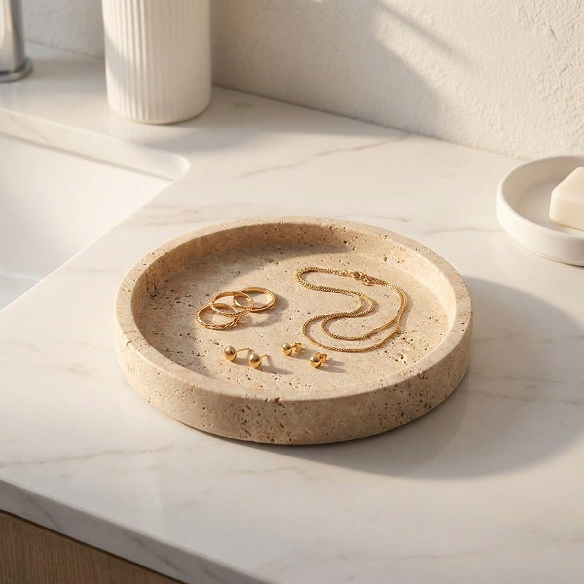 Plateau travertin avec bijoux dorés sur marbre blanc