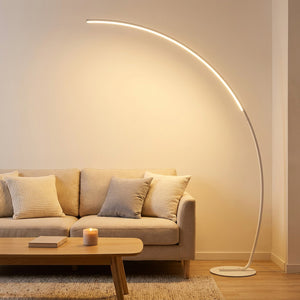 Lampadaire LED arc blanc dans un salon cosy scandinave avec canapé beige et table basse