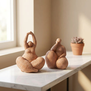Deux statuettes de femme en résine sableuse posées sur une console en marbre blanc