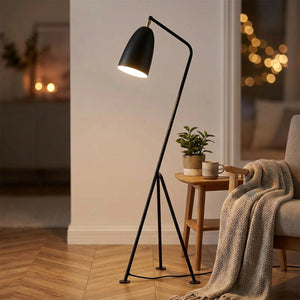 Lampadaire trépied noir près d'une table d'appoint en bois avec une plante