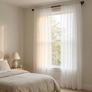 Voilage blanc suspendu dans une chambre cosy avec lit et lampe de chevet