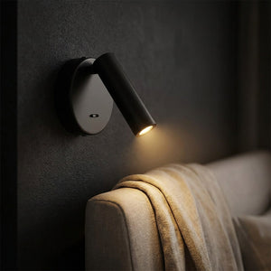 Applique murale ronde noire en gros plan avec plaid beige et lumière chaude tamisée