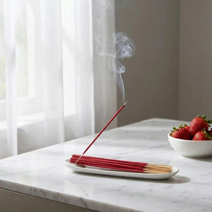 Bâtons d'encens rouge brûlant sur surface marbre blanche près fenêtre voilage zen