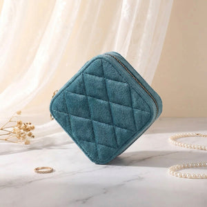 Coffret à bijoux velours bleu canard fermé en diamant sur surface marbre près de voilage