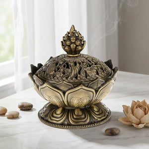 Porte-encens Bouddha bronze sur surface en marbre près d'une fenêtre avec galets et fleur séchée