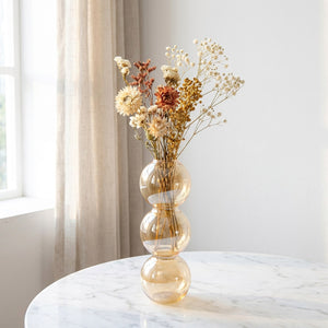 Vase en verre champagne style nordique avec fleurs séchées sur marbre