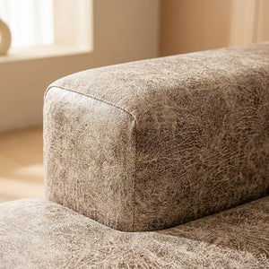 Gros plan sur l'angle d'un coussin recouvert par la housse beige taupe effet cuir
