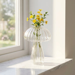 Vase champignon verre transparent avec fleurs jaunes sur rebord fenêtre lumière naturelle