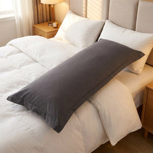 Taie de traversin gris posée en diagonale sur un lit fait dans une chambre cosy