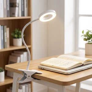 Lampe de bureau à pince éclairant un carnet et un ordinateur portable sur un bureau