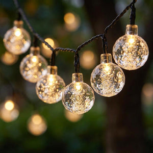 Gros plan boules cristal guirlande LED solaire lumière chaude bokeh
