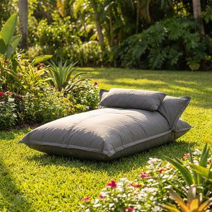 Pouf flottant gris installé sur une pelouse entourée de fleurs de jardin