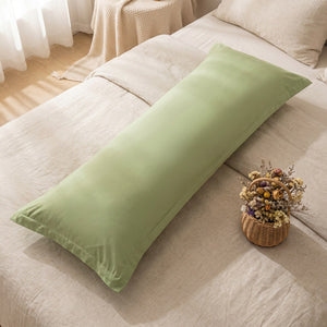 Taie de traversin verte vue de dessus sur un lit avec panier de fleurs séchées