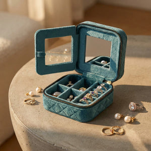 Boîte à bijoux ouverte sur table béton dorée avec boucles et bagues disposées autour