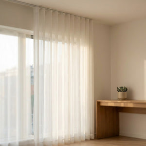 Rideau voile blanc suspendu près d'un bureau en bois avec une plante grasse