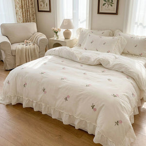Parure de lit brodée de roses dans une chambre lumineuse avec fauteuil cosy