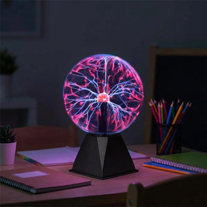 Lampe boule de plasma allumée sur un bureau d'enfant avec livres et fournitures