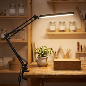 Lampe de bureau architecte noire clampée sur un établi en bois