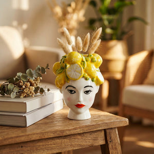 Vase céramique tête de femme aux citrons sur une table en bois rustique avec pampa et livres