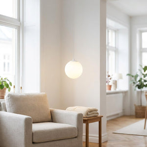 Suspension boule en verre opalin blanche dans un salon scandinave lumineux