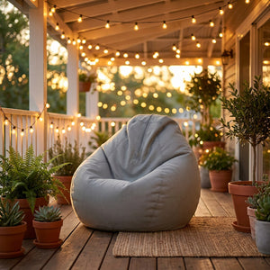 Housse de pouf poire grise sur une terrasse couverte le soir avec guirlande lumineuse