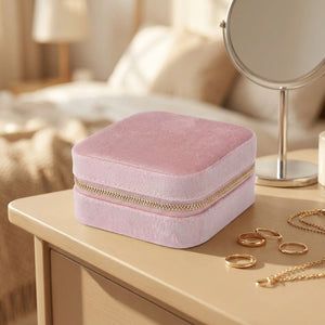 Boîte à bijoux en velours rose fermée posée près d'un miroir sur une coiffeuse