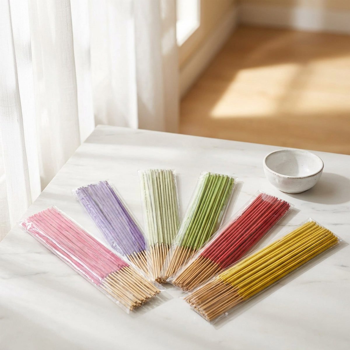 Bâtons d'encens colorés disposés sur surface marbre près d'une fenêtre lumineuse