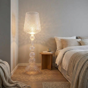 Lampadaire acrylique transparent ajouré allumé dans un coin de chambre nordique