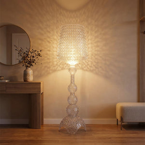Lampadaire acrylique transparent ajouré allumé dans une entrée projetant des ombres de dentelle