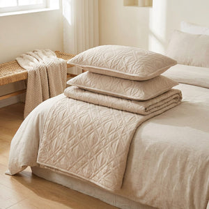 Ensemble couvre-lit et taies beige plié au pied d'un lit