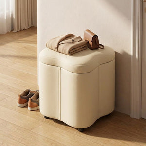 Tabouret coffre crème utilisé comme siège dans une entrée avec un manteau plié et un sac posés dessus