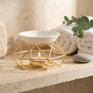 Brûle-parfum à bougie support métal doré sur une étagère de salle de bain avec serviettes et eucalyptus