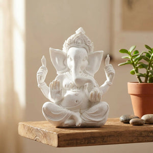 Statue Ganesh blanche sur une étagère en bois avec une plante verte