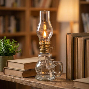 Lampe à pétrole en verre allumée sur une étagère avec des livres anciens et une plante