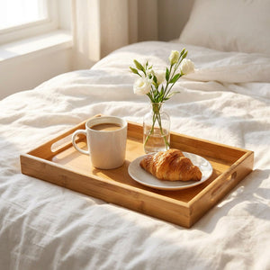 Plateau en bambou sur lit blanc avec petit-déjeuner café croissant et fleurs
