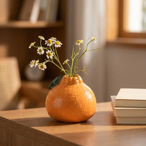Vase en forme d'orange avec des marguerites blanches sur un bureau cosy
