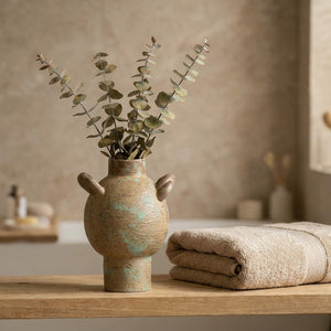 Vase rustique boule en céramique sur une étagère de salle de bain avec eucalyptus