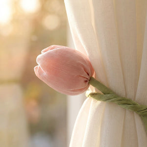 Gros plan sur la fleur de tulipe rose en tissu et sa tige verte contre un voilage