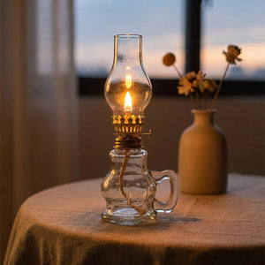 Lampe à pétrole rétro allumée sur une table en lin près d'une fenêtre au crépuscule