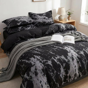 Parure de lit effet marbre noir sur un lit cocooning avec un plaid gris