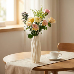 Vase origami blanc sur une table avec un bouquet pastel et une tasse à café