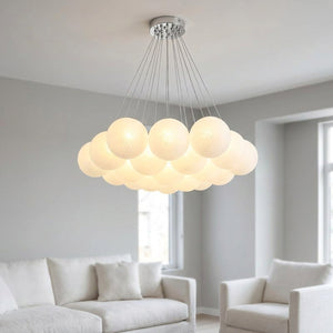 Lustre à boules de verre blanc laiteux avec cadre argenté suspendu dans un salon moderne minimaliste lampe allumée