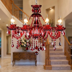 Lustre en cristal rouge allumé dans une entrée luxueuse avec escalier et console