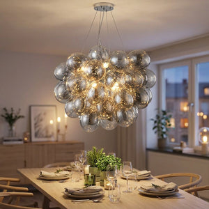 Lustre grappe boules en verre suspendu au-dessus d'une table à manger lumière douce ambiance nordique