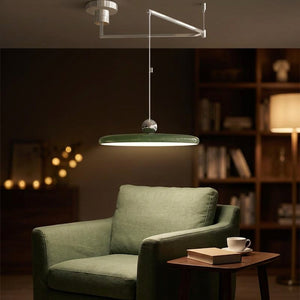 Lustre pendentif LED vert émeraude dans un coin lecture cosy avec fauteuil et bibliothèque