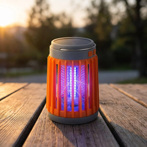 Lampe anti-moustiques solaire UV rechargeable orange allumée sur table extérieure
