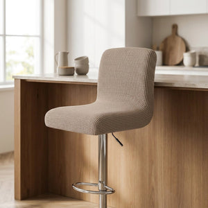 Housse de chaise de bar en jacquard texturé beige installée sur un tabouret dans une cuisine lumineuse