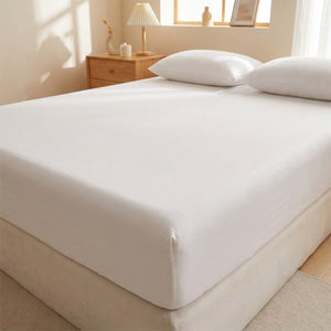 Drap housse blanc délavé avec bandes élastiques installé sur un matelas dans une chambre lumineuse